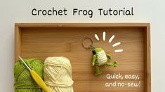 crochet frog keychain, yarn and scissors in a wooden tray with the words crochet frog on it