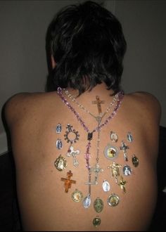 the back of a woman's body with many different necklaces on her chest