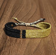 two braided bracelets sitting on top of a wooden table