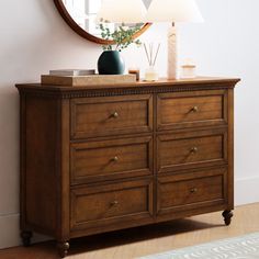 a wooden dresser with a mirror and lamp on top