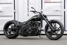 a black motorcycle parked in front of a white container