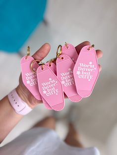 four pink tags with words on them are held in someone's hand, which is also attached to the wrist