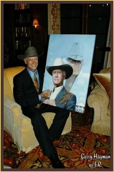 a man sitting in a chair with a painting on it's lap and smiling at the camera