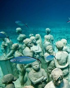 an underwater scene with statues and fish in the water