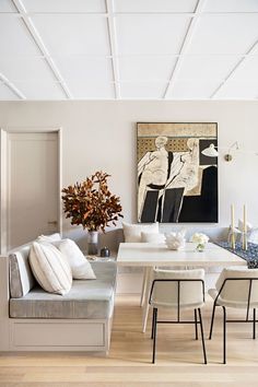 an instagram photo of a living room and dining room with white walls, wood flooring and artwork on the wall