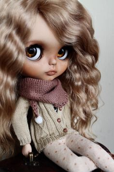 a doll with long blonde hair sitting on top of a table