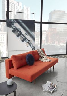 an orange couch sitting in front of a large window