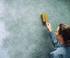 a woman is painting the wall with a brush