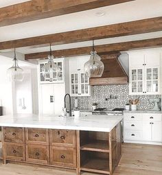 a large kitchen with white cabinets and wooden beams on the ceiling is pictured in this image