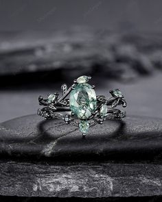 a green ring with leaves on it sitting on top of a rock in front of a black and white background