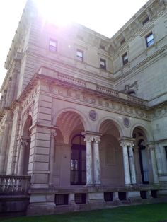 the sun shines brightly on an old building with columns and arched doorways in front of it