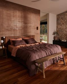a large bed sitting in the middle of a bedroom next to a mirror and wooden floor