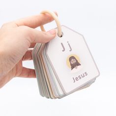 a hand holding a stack of cards with jesus on it and the word j is spelled in small letters