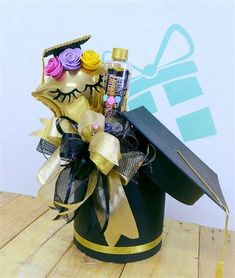 a black graduation hat with gold ribbon and flowers in it on top of a wooden table