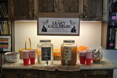 some jars and cups are sitting on the counter in front of a sign that reads leaky cauldon