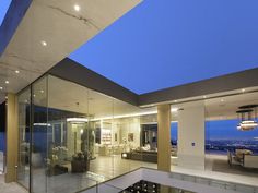 the interior of a modern home with glass walls and floor to ceiling windows looking out onto the city