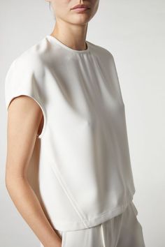 Introducing the Soraya Cap Sleeve Top, a symbol of refined comfort and timeless elegance. Crafted from luxurious Ivory Crepe fabric, this top ensures a pristine appearance that remains unwrinkled throughout wear. Its easy fit and relaxed tailoring guarantee effortless sophistication, making it a versatile choice for any occasion. Boasting a single button closure at the back for a clean finish, the Soraya top exudes understated grace. With easy cap sleeves and a flattering silhouette, it epitomiz Relaxed Tailoring, Saint Art, Crepe Top, Outerwear Vest, Cap Sleeve Top, New Pant, Knitwear Tops, Denim Flares, Crepe Fabric