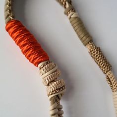 an orange and white rope is attached to the end of a piece of string on a white surface