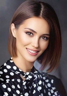 a woman with brown hair and polka dot blouse smiling at the camera, wearing a black and white collared shirt