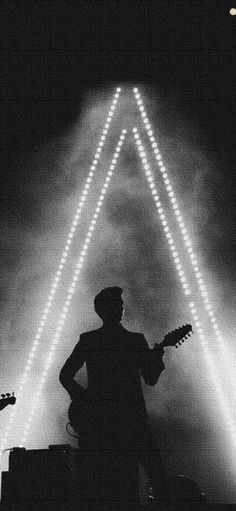 a man with a guitar standing in front of some lights