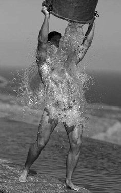 a man is splashing water on his head with a bucket