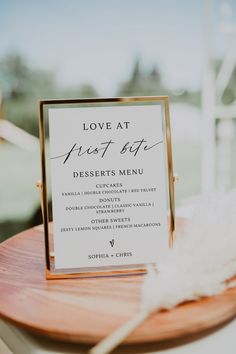 a sign that says love at first bite desserts menu sitting on a wooden plate