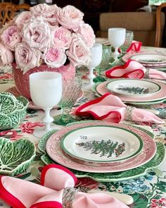 the table is set with pink flowers and green plates, napkins and place settings