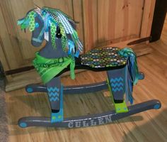 a child's wooden rocking horse with green, blue and white ribbons on it