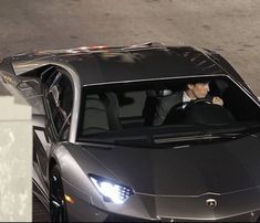 a man sitting in the drivers seat of a sports car with his headlight on