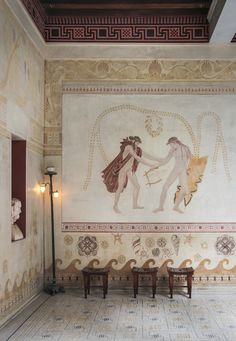 two people are touching hands in front of a wall with paintings on it and benches