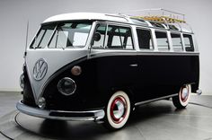 a black and white vw bus parked on top of a cement floor next to a wall