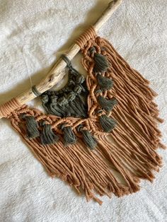 a wooden stick with tassels on it laying on a white surface next to a piece of cloth