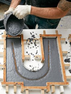 a man is working on an object in the process of being made with wood and cement