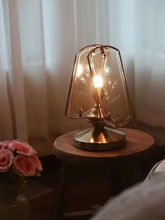 a table lamp sitting on top of a wooden table next to a vase with flowers