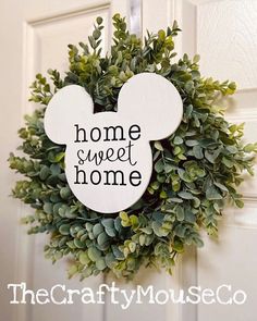 a mickey mouse wreath with the words home sweet home hanging on it's front door