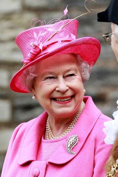 the queen smiles as she stands next to an older woman in pink and white attire