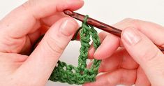 two hands crocheting the end of a piece of green yarn