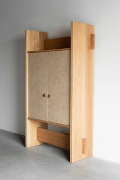 a wooden cabinet sitting on top of a cement floor next to a white wall and door