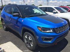 a bright blue jeep parked in a parking lot next to other white suv's