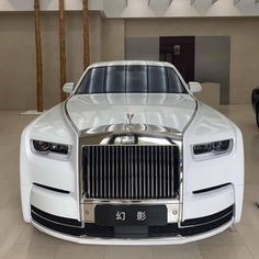 a white rolls royce parked in a showroom next to another car with chinese writing on the front