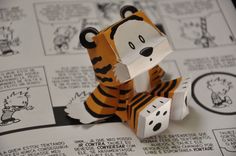 an origami tiger sitting on top of a book with dices in front of it