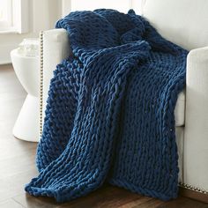 a blue knitted blanket sitting on top of a white couch