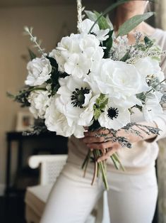 a woman holding a bouquet of white flowers