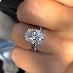 a woman's hand with a diamond ring on top of her finger and an engagement band