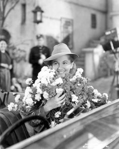 a black and white photo of a woman in a car with flowers on her lap