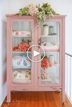 an old china cabinet is painted pink with flowers on the top and bottom, along with decorative items