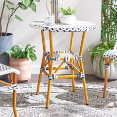 two chairs and a table in a room with plants on the floor, one has a potted plant next to it