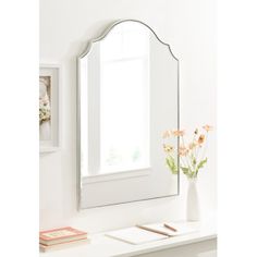 a mirror sitting on top of a white table next to a vase with flowers in it