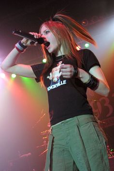 a woman with long hair holding a microphone in front of her head and singing on stage