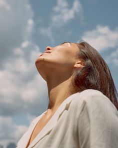 a woman looking up into the sky with her eyes closed and head tilted to the side